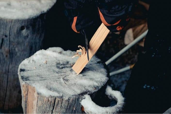 person sharpening wood plank