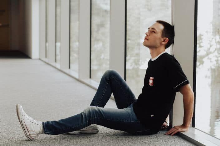 man sitting and leaning on white pillar