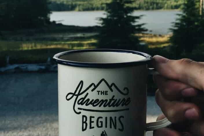 person holding cup near lake
