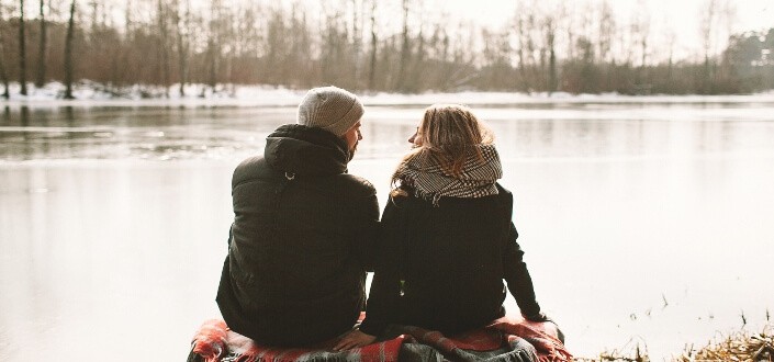couple sitting beside a lake