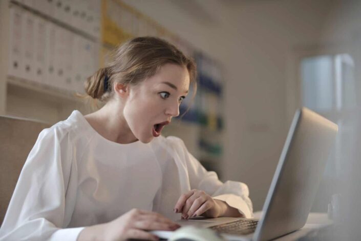 woman having shocked expression in front of laptop