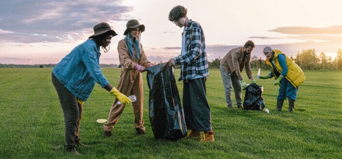 people picking trash on grass field