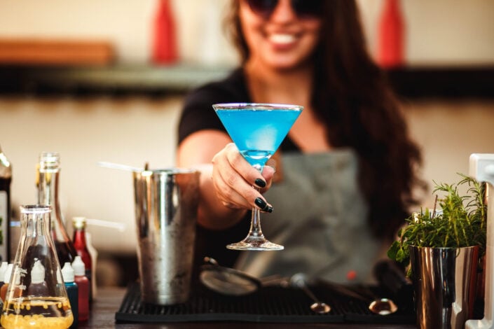 Woman holding cocktail glass with blue liquid