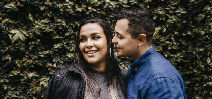 Smiling woman with boyfriend near hedge
