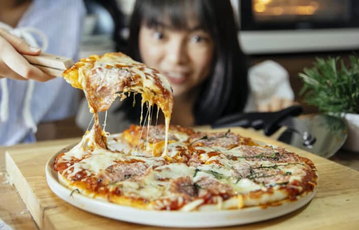 Excited women taking piece of pizza