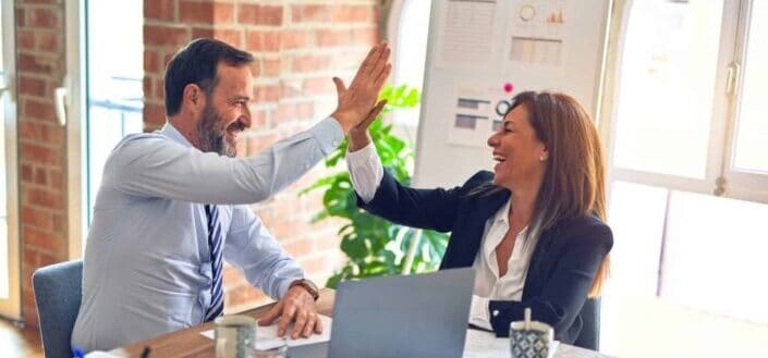 Coworkers delightedly doing a high five