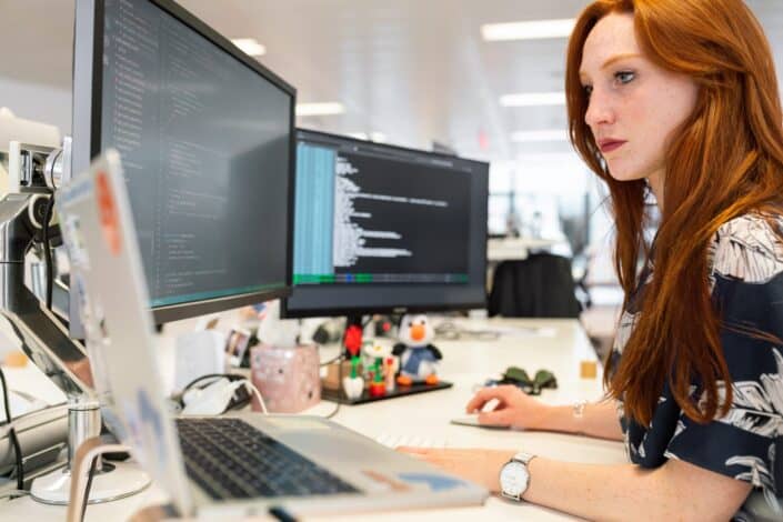 Woman working in front of multiple monitor computer