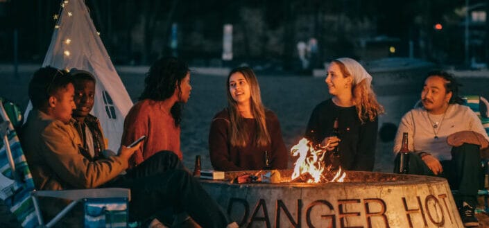 Group of friends sitting in front of fire pit