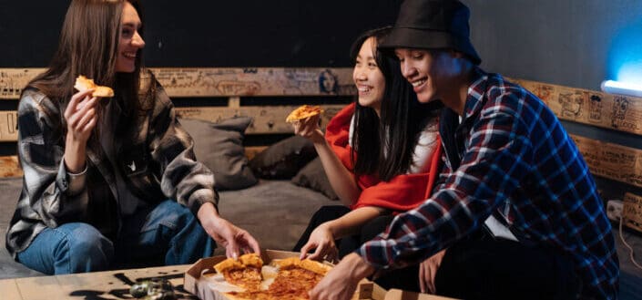 Happy friends hanging out together and eating pizza
