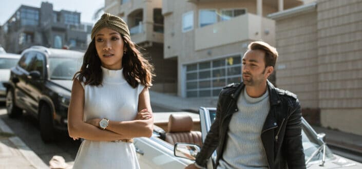 Man and woman standing beside white car having a discussion