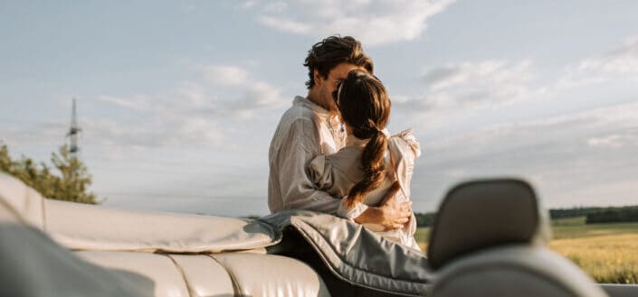 Man and Woman Kissing Outside Their Car