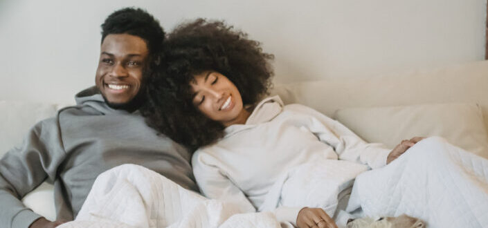 Delighted young couple cuddling on bed