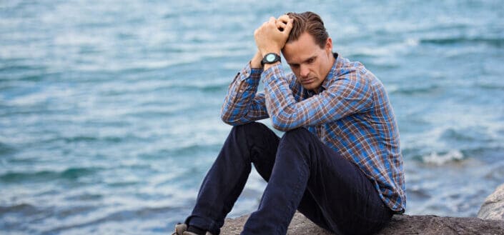 Man Sitting on a Rock Near a Body of Water