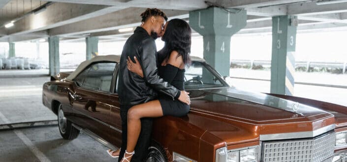 Woman Sitting on a Car Hood Kissing a Man