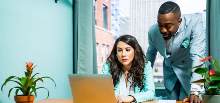 Man Beside a Woman Using a Laptop