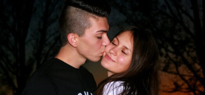 Guy kissing her girlfriend on her cheeks