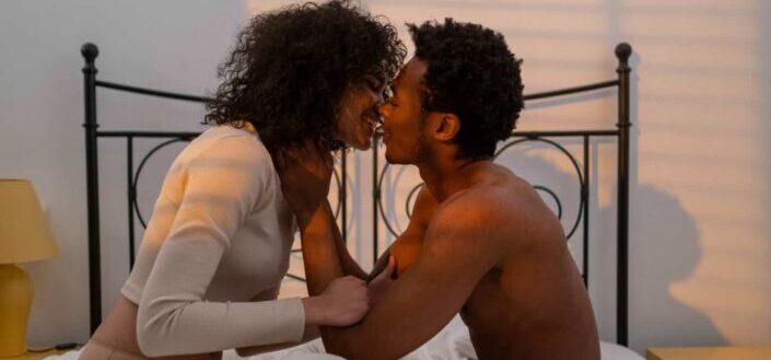 Couple sitting on bed and kissing