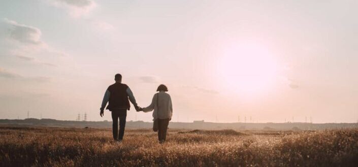 Man and Woman Walking on a Grassy Field