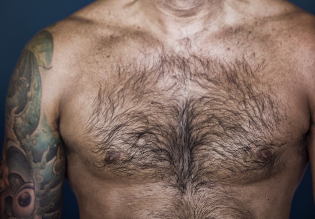 Rugged confidence. Portrait of mature man with full and natural chest hair posing against a dark background