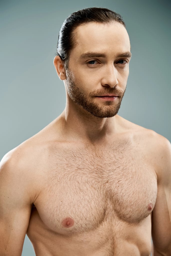Handsome man with a beard stands shirtless with a natural but groomed chest hair style.