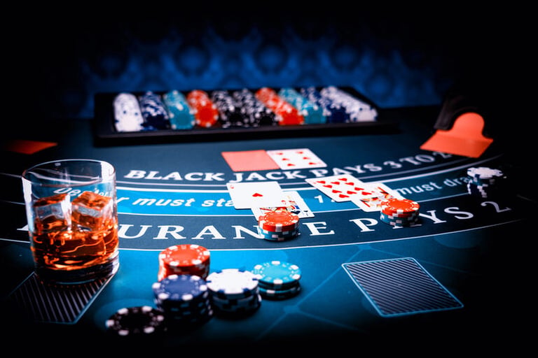Close-up of a blackjack table with cards, poker chips, and a glass of whiskey