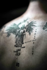 Tattoo art on the back and spine incorporating the Latin phrase Merentur somnium tuum – "They deserve your dream."