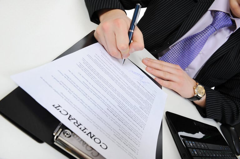 Business professional signing an employment contract at a desk.