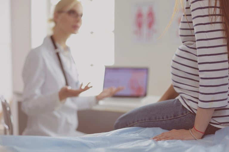A pregnant woman sitting on an examination bed speaking with a healthcare professional in a bright medical office, highlighting the supportive environment of private obstetric care.