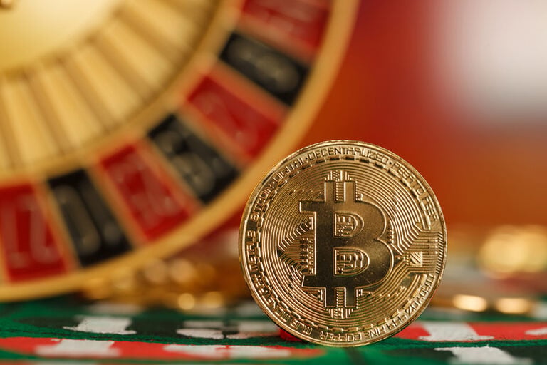 A bitcoin coin in front of a casino roulette
