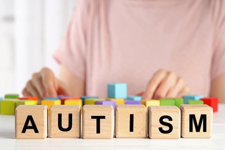 A set of blocks with letters that read autism, a man in the background
