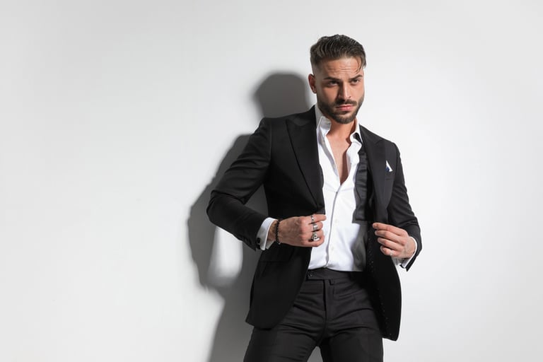 Male fashion model in a black suit adjusting his jacket in a studio, representing organization and professionalism in modeling work.