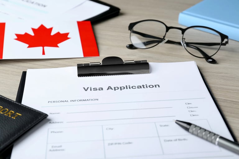 Visa application form on a desk beside a Canadian flag, passport, glasses, and a pen.