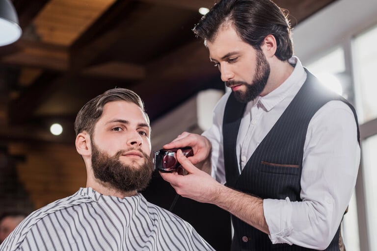 A man is having his beard trimmed by a barber