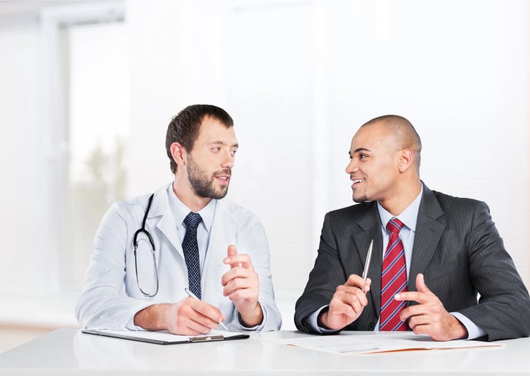 Two male healthcare professionals discussing career opportunities in a medical office setting.