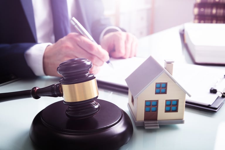 Real estate legal process shown with a gavel, house model, and signed documents.