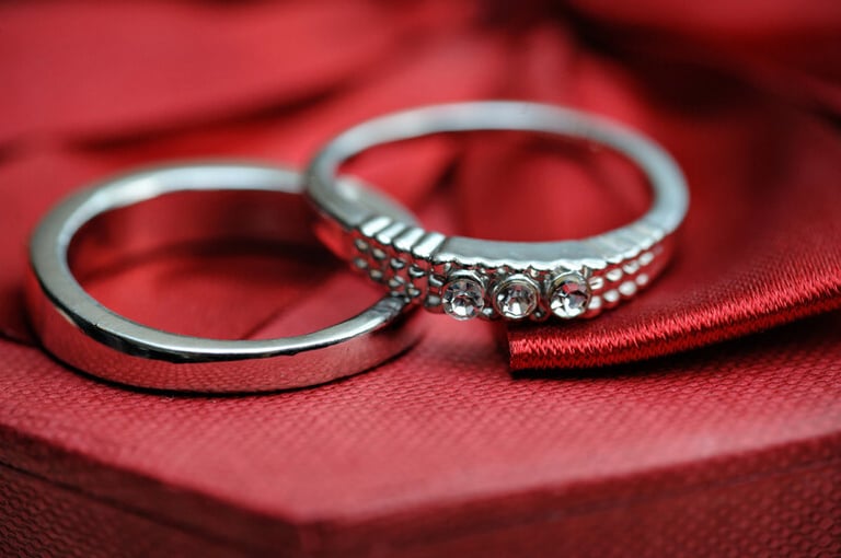 Close-up of two elegant wedding rings resting on rich red fabric, highlighting the subtle beauty and symbolism of commitment