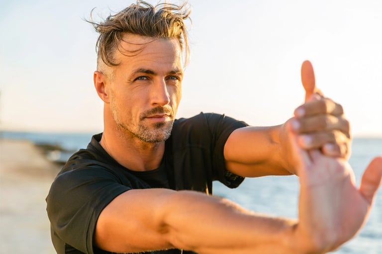 A man is exercising before doing sports at a beach.