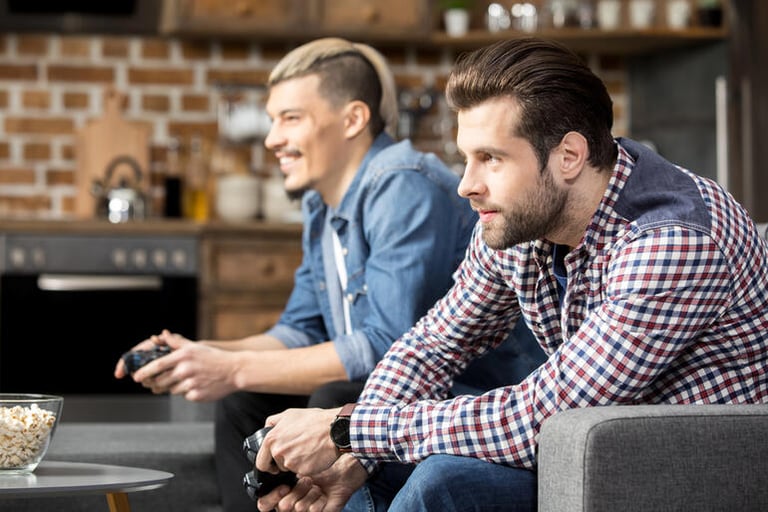 Two men relaxing on a sofa playing a video game, representing luxury leisure and modern gentleman entertainment choices