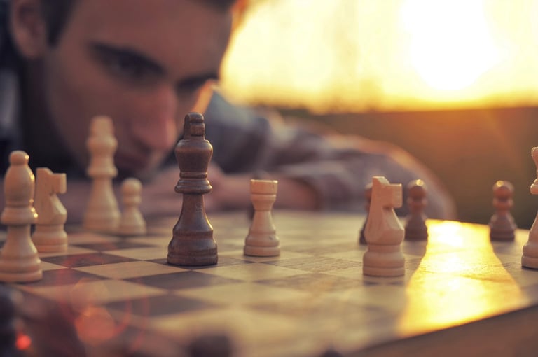 A young man focused intensely on a chessboard during sunset, illustrating how games can boost strategic thinking