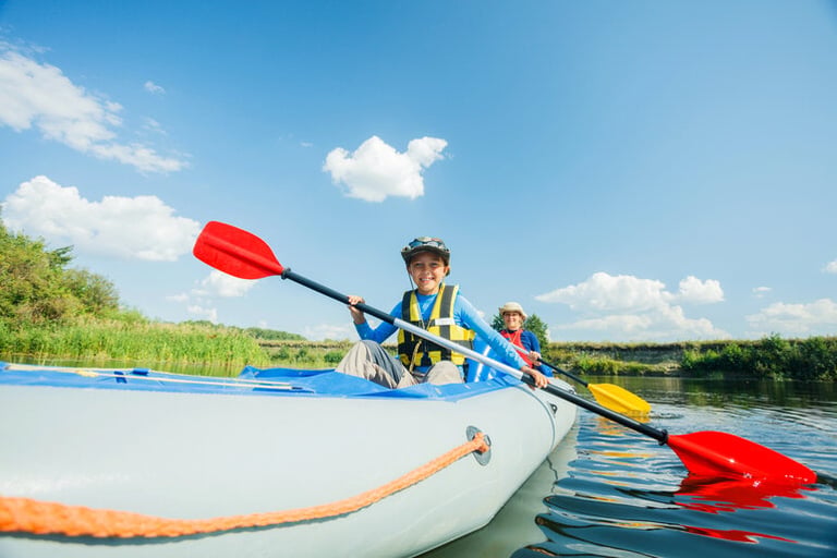 A man teaching his kid basic boating skills while kayaking on a calm river