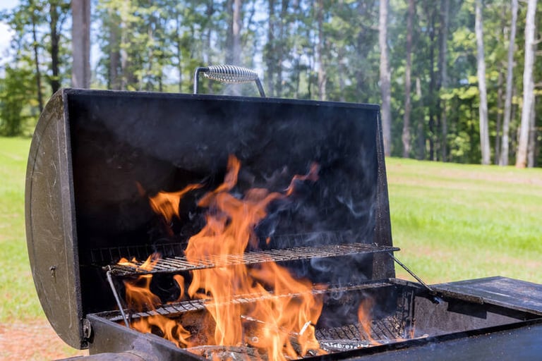 Flames rising from an outdoor charcoal grill during a flare-up in a backyard setting
