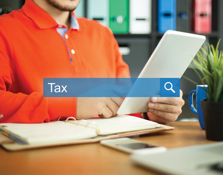 A startup professional using a tablet at a desk with a notebook and coffee, searching for tax information, representing business tax preparation, planning, and organization