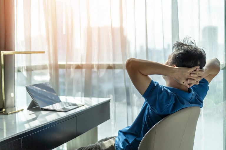 A man sitting on a chair with his hands on his head.