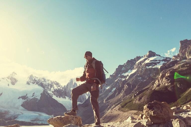 Hiker standing on a mountain peak, symbolizing risk-taking and adventure.