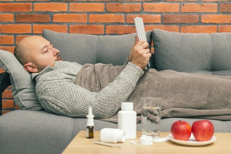 Man lying on a sofa using an iPad.
