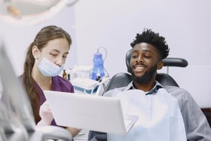 Man receiving dental treatment from a female dentist in a clinical setting, showing a calm and professional dental care environment.