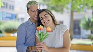 A smiling woman happily holding a bouquet of fresh flowers, capturing the thoughtful and romantic gesture often associated with the early stages of dating.