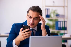 Concerned man in an office staring at his phone, illustrating dating app burnout from endless matches and a lack of meaningful connections.