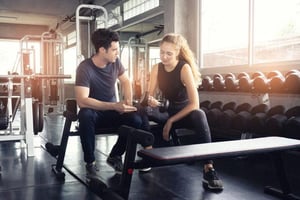A personal trainer guiding a client in a dumbbell exercise, demonstrating how coaches can help individuals achieve their fitness objectives.
