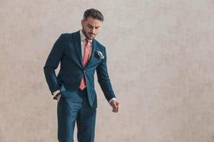 Confident man in a tailored blue suit with a bold red tie, adjusting his look with a composed, self-assured expression, reflecting modern men redefining personal style and fashion rules.